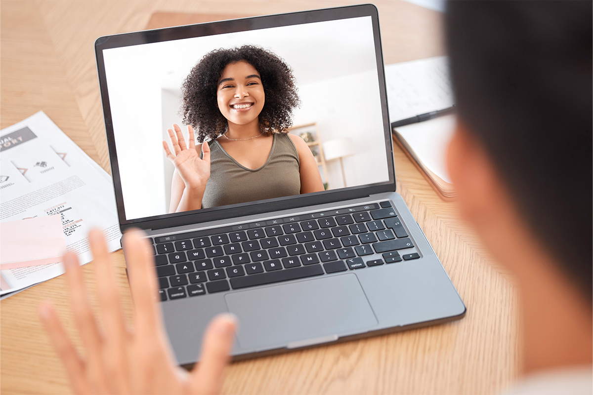 A happy Ad Astra Video Interpretation client is seen waving through a laptop screen. 
